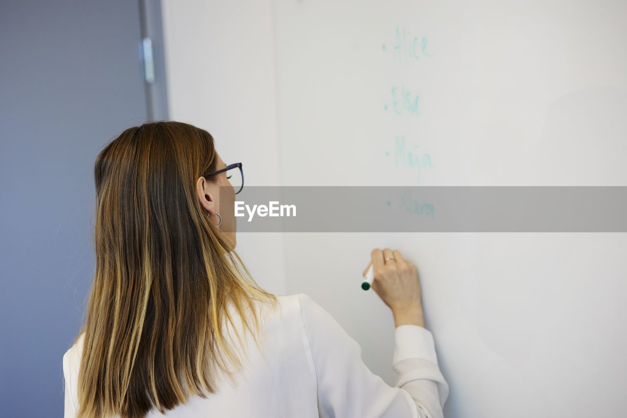 Woman writing on whiteboard during meeting