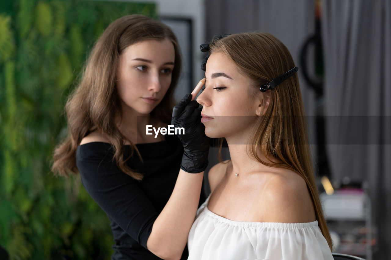 Close-up of of woman applying make-up to customer