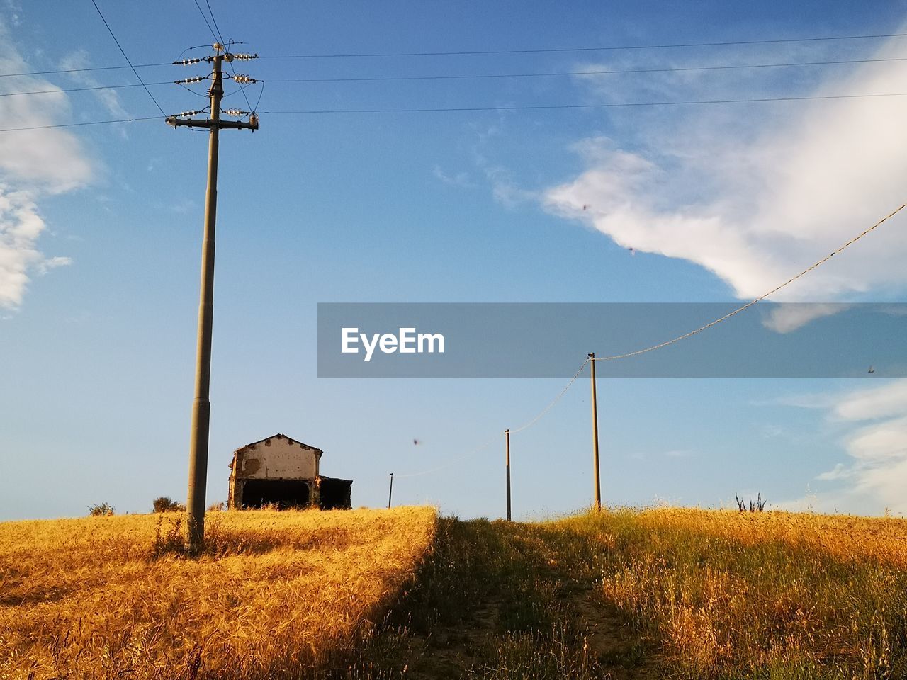 ELECTRICITY PYLON ON FIELD AGAINST SKY