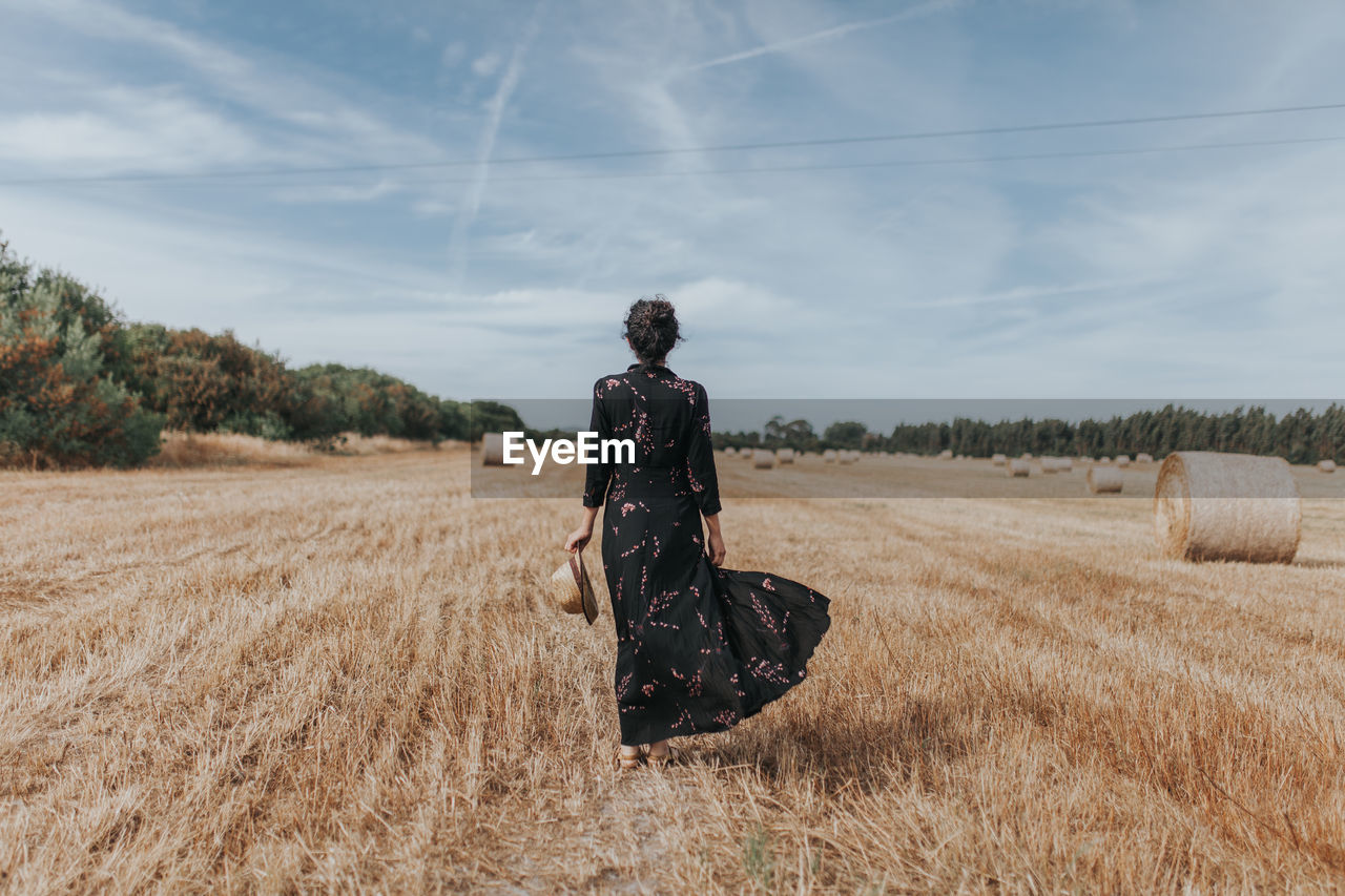 Rear view of woman on agricultural field against sky