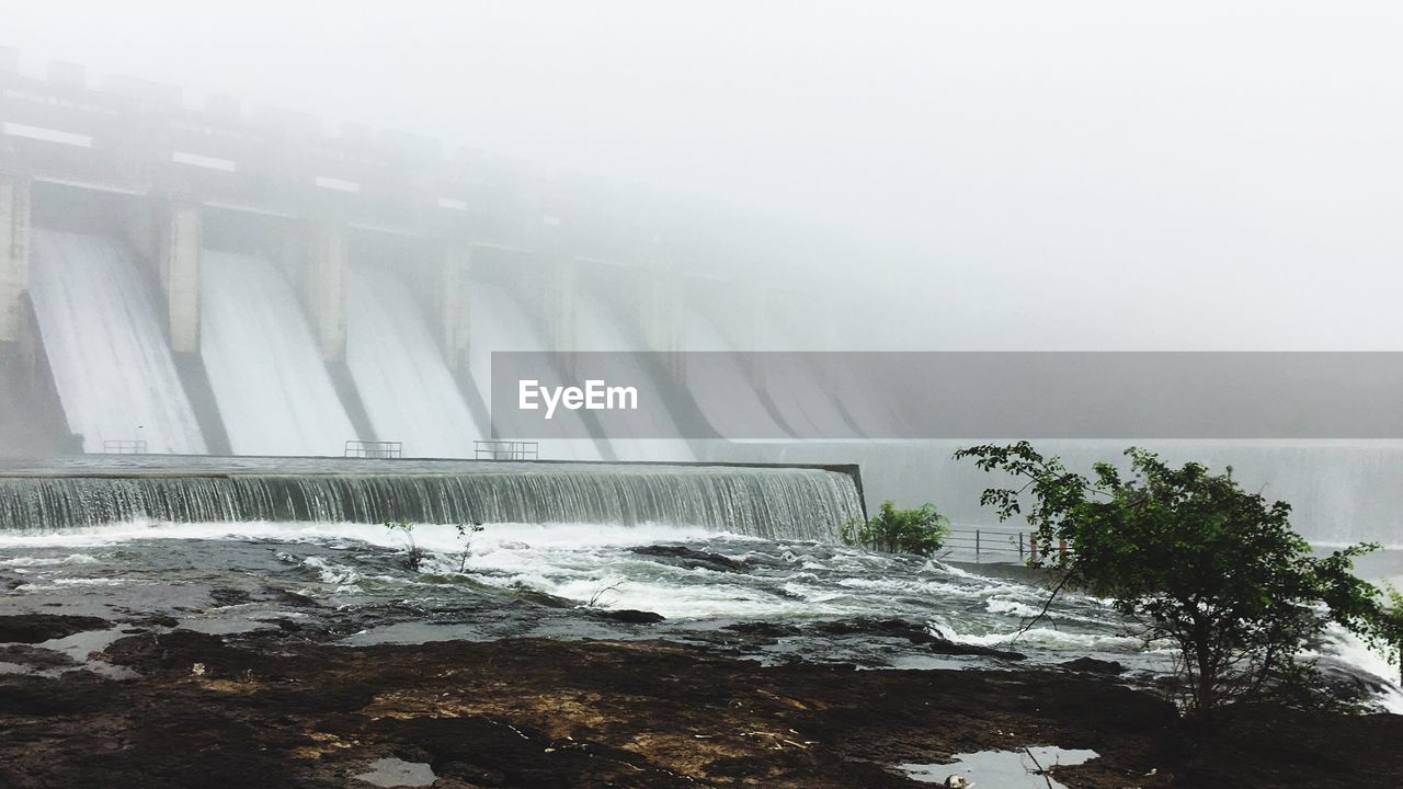 Water flowing from dam during foggy weather