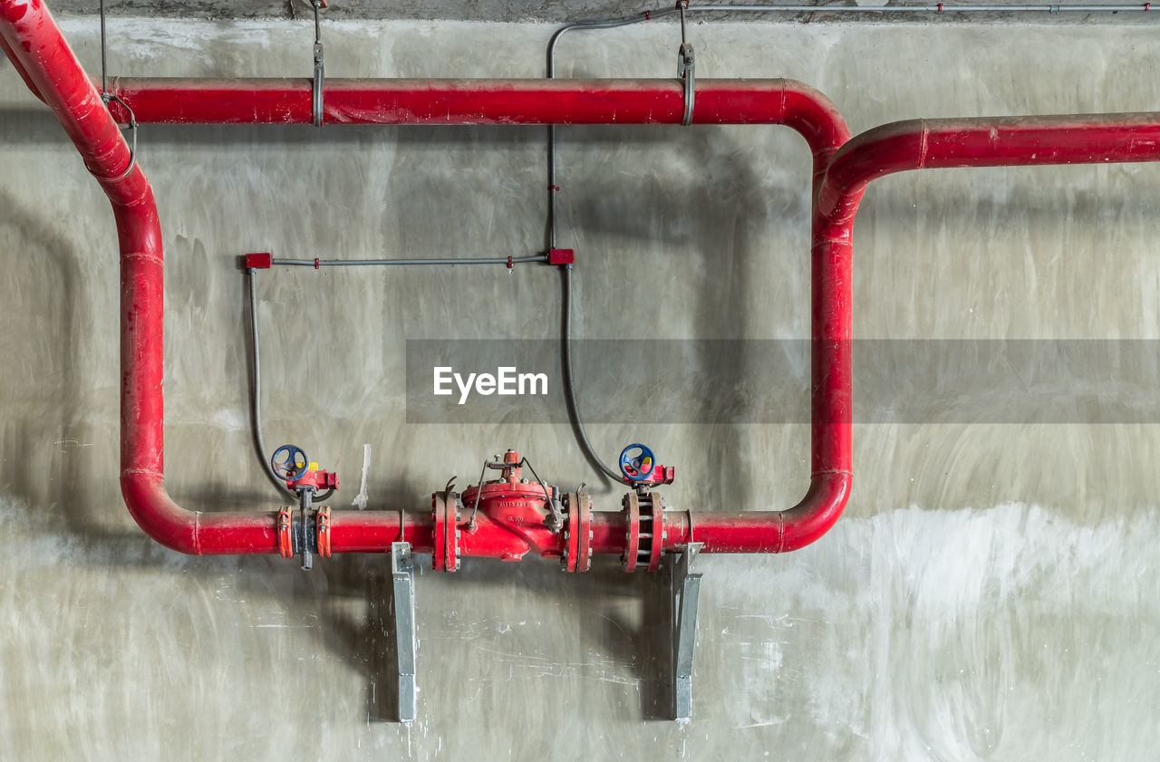 RED PIPE AGAINST WALL IN BUILDING