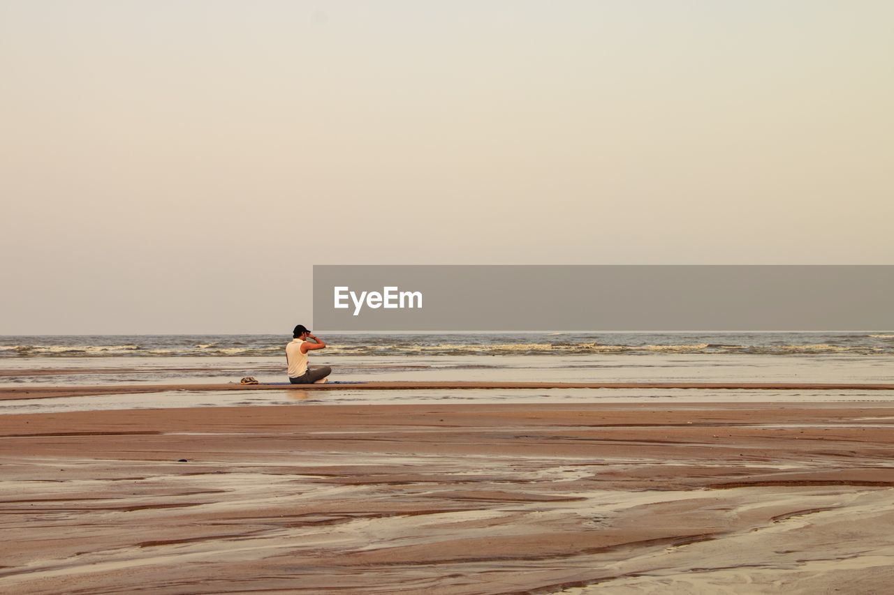 Man at beach against clear sky