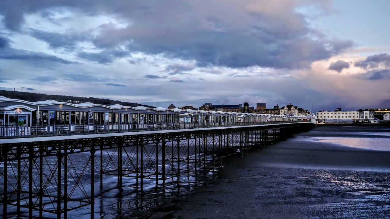 Restaurant on bridge against cloudy sky