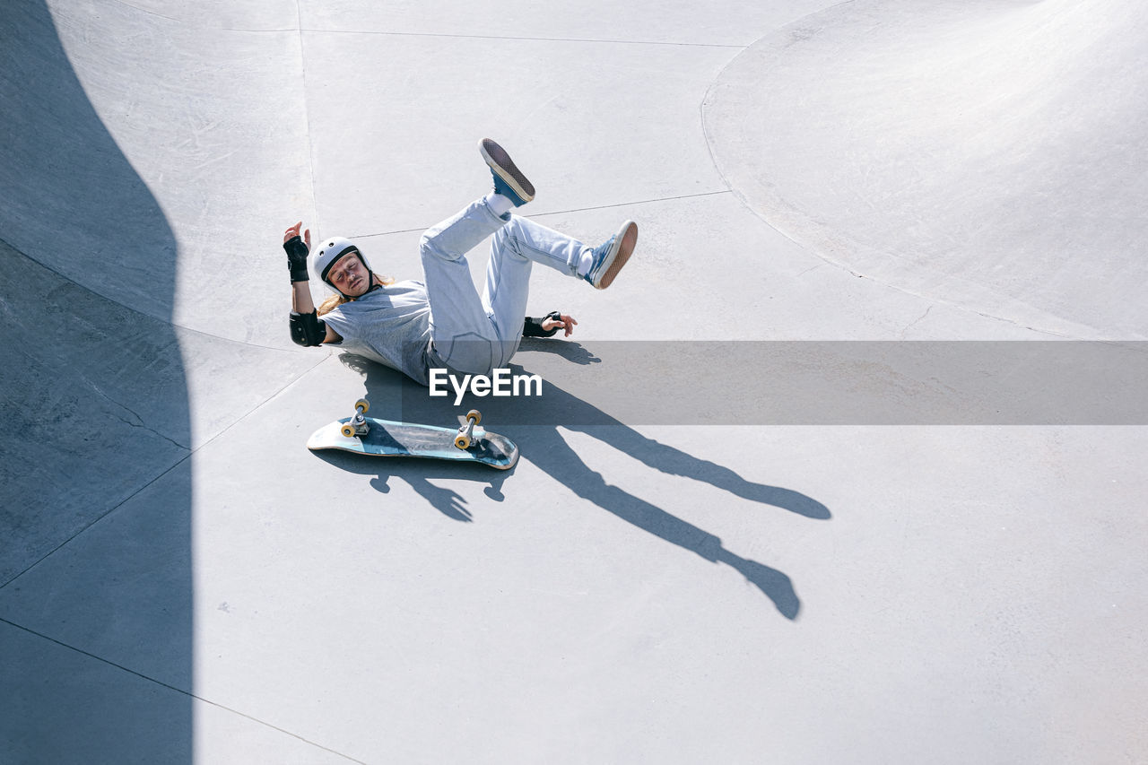 Skateboarder falling in skatepark on sunny day