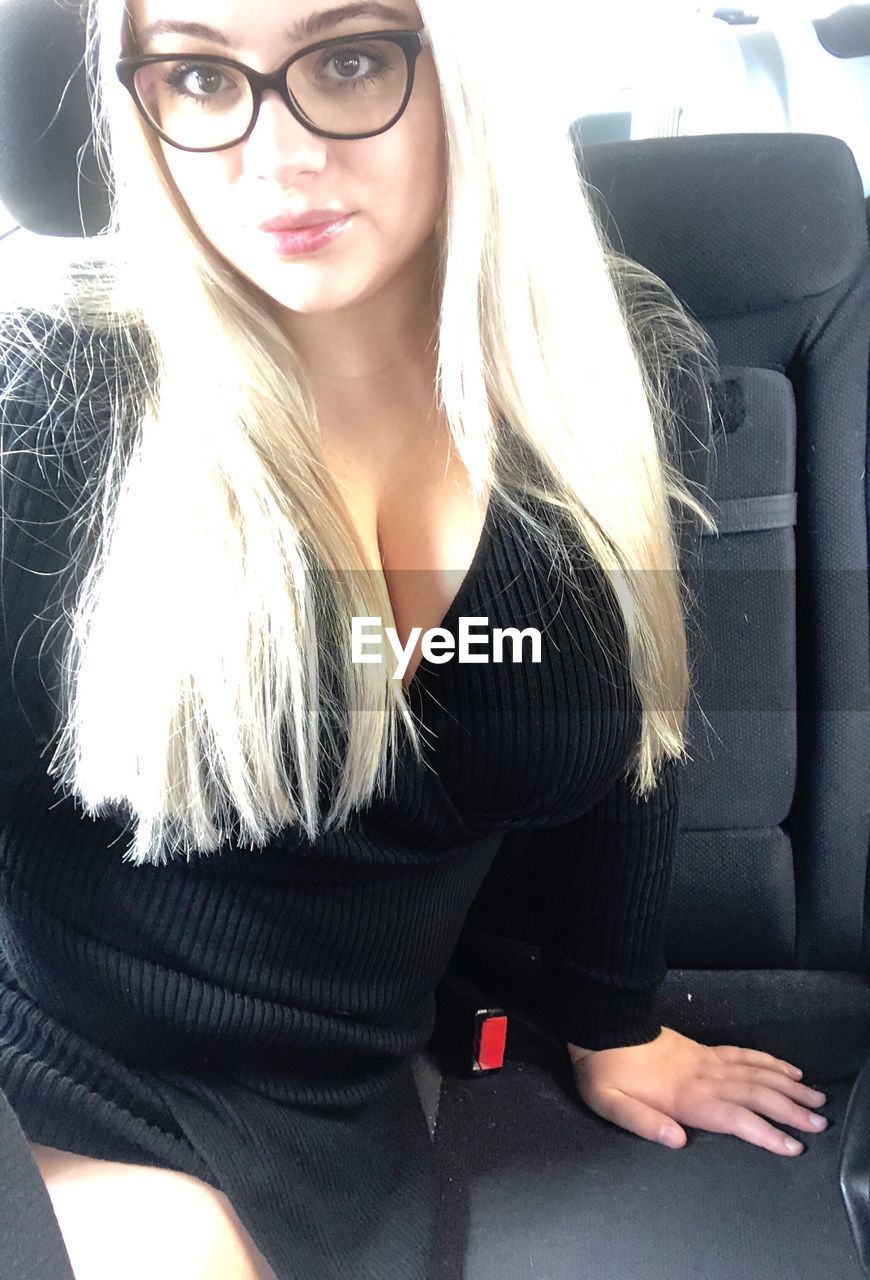 BEAUTIFUL YOUNG WOMAN SITTING IN CAR WITH UMBRELLA