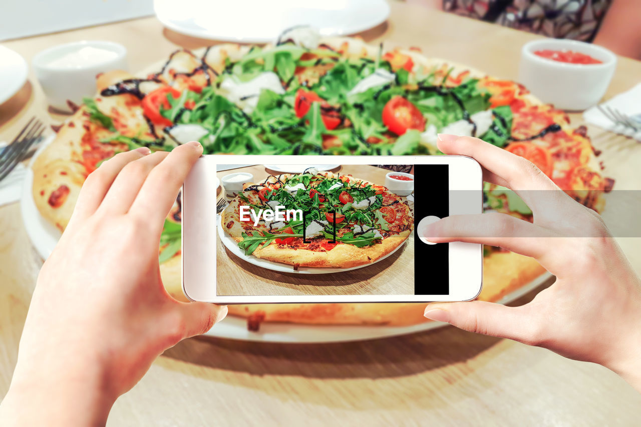 MIDSECTION OF MAN PHOTOGRAPHING FOOD WITH MOBILE PHONE
