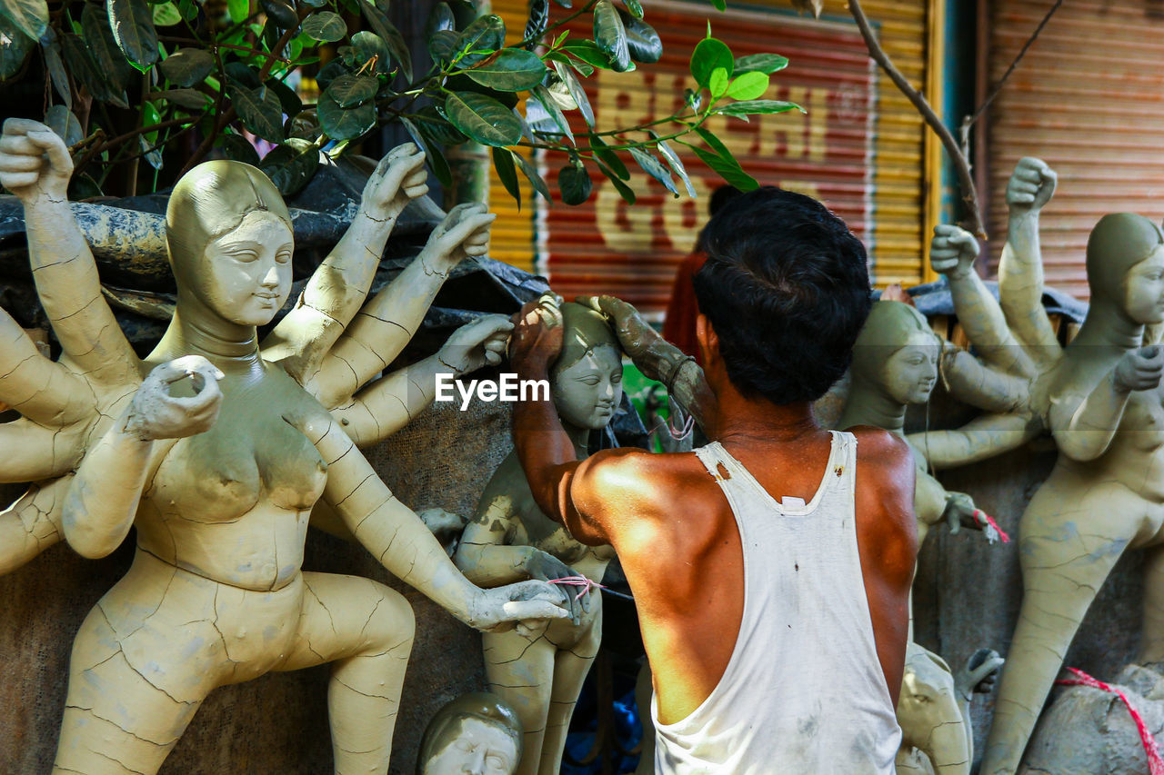 REAR VIEW OF MAN STATUE AT TEMPLE