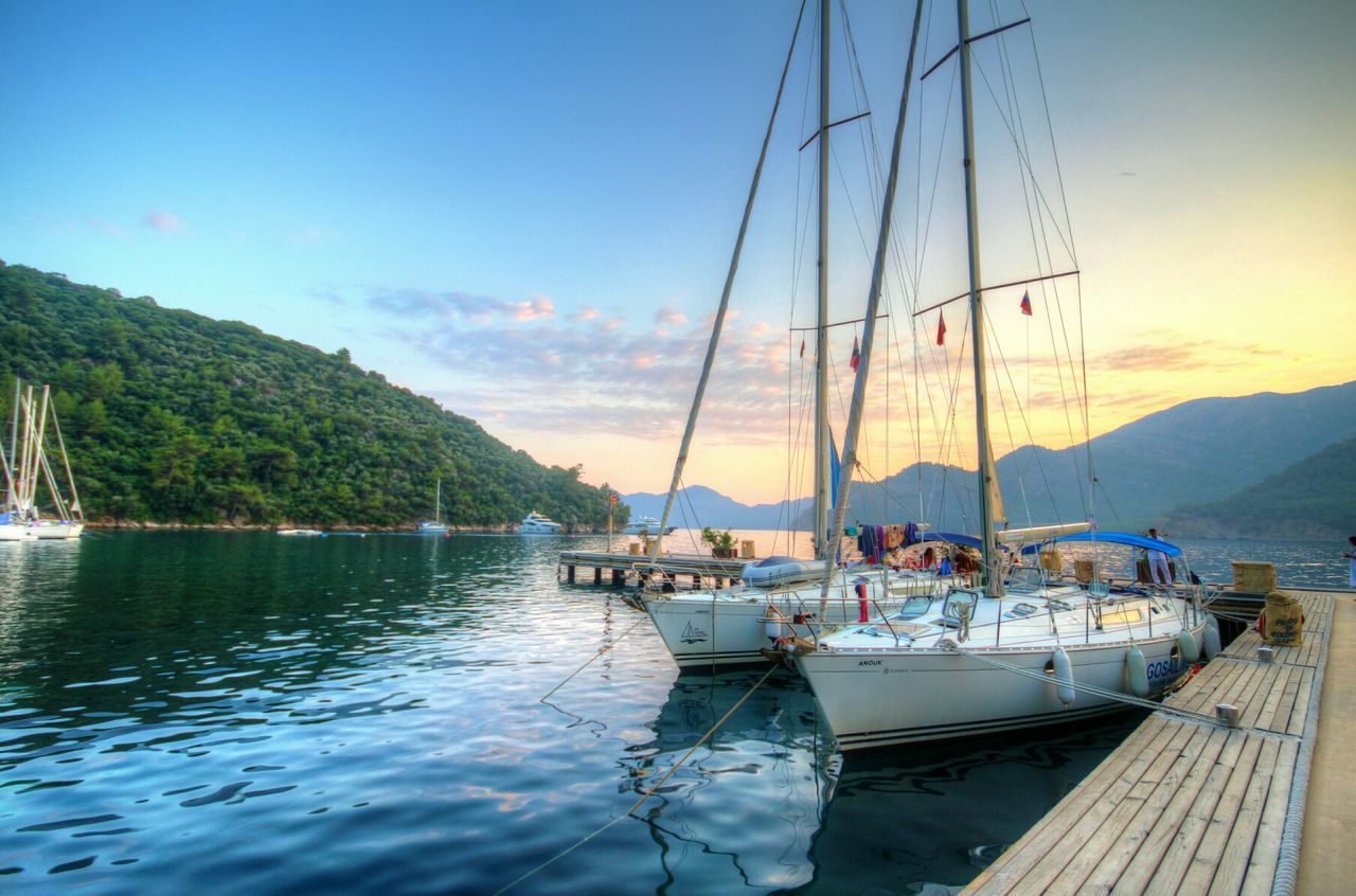 Boats moored by pier against clear blue sky