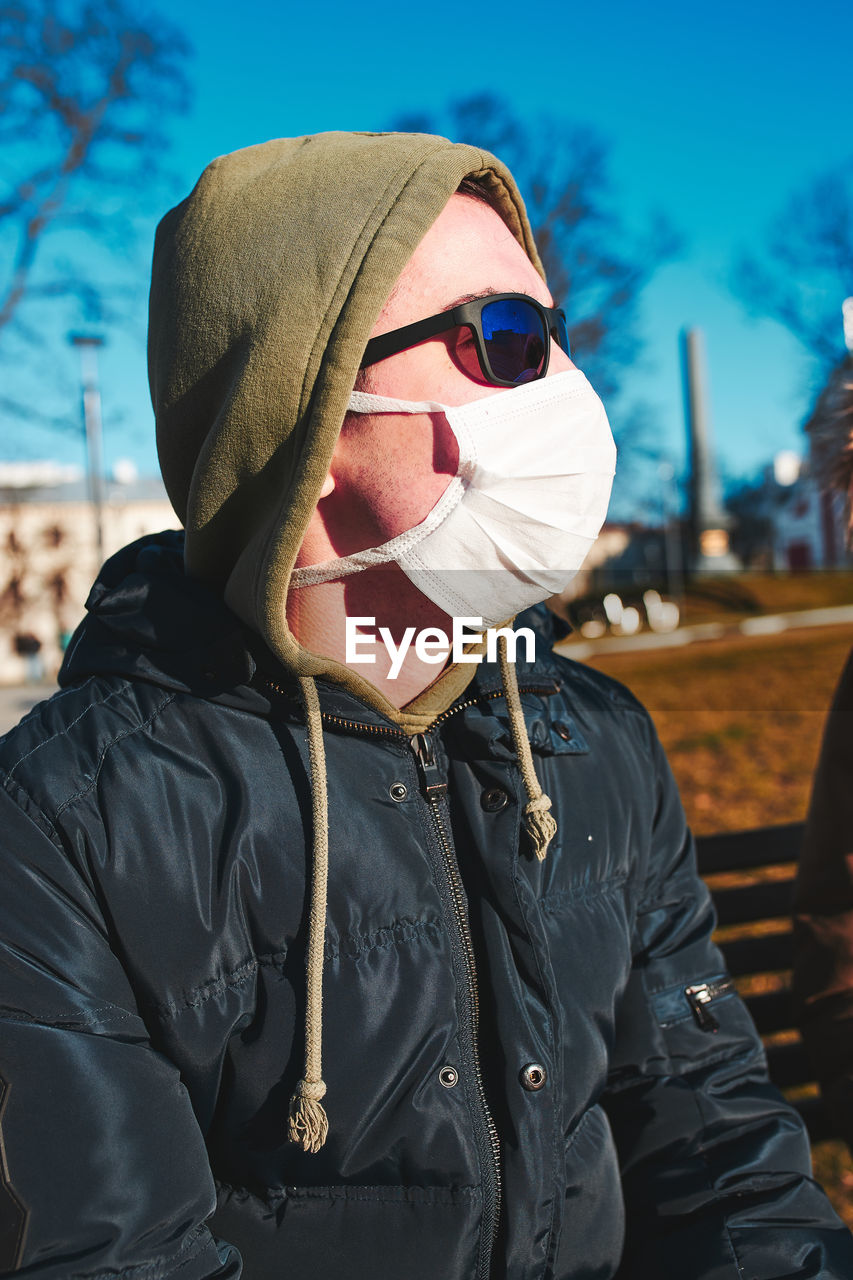 MIDSECTION OF MAN WEARING SUNGLASSES STANDING IN SNOW