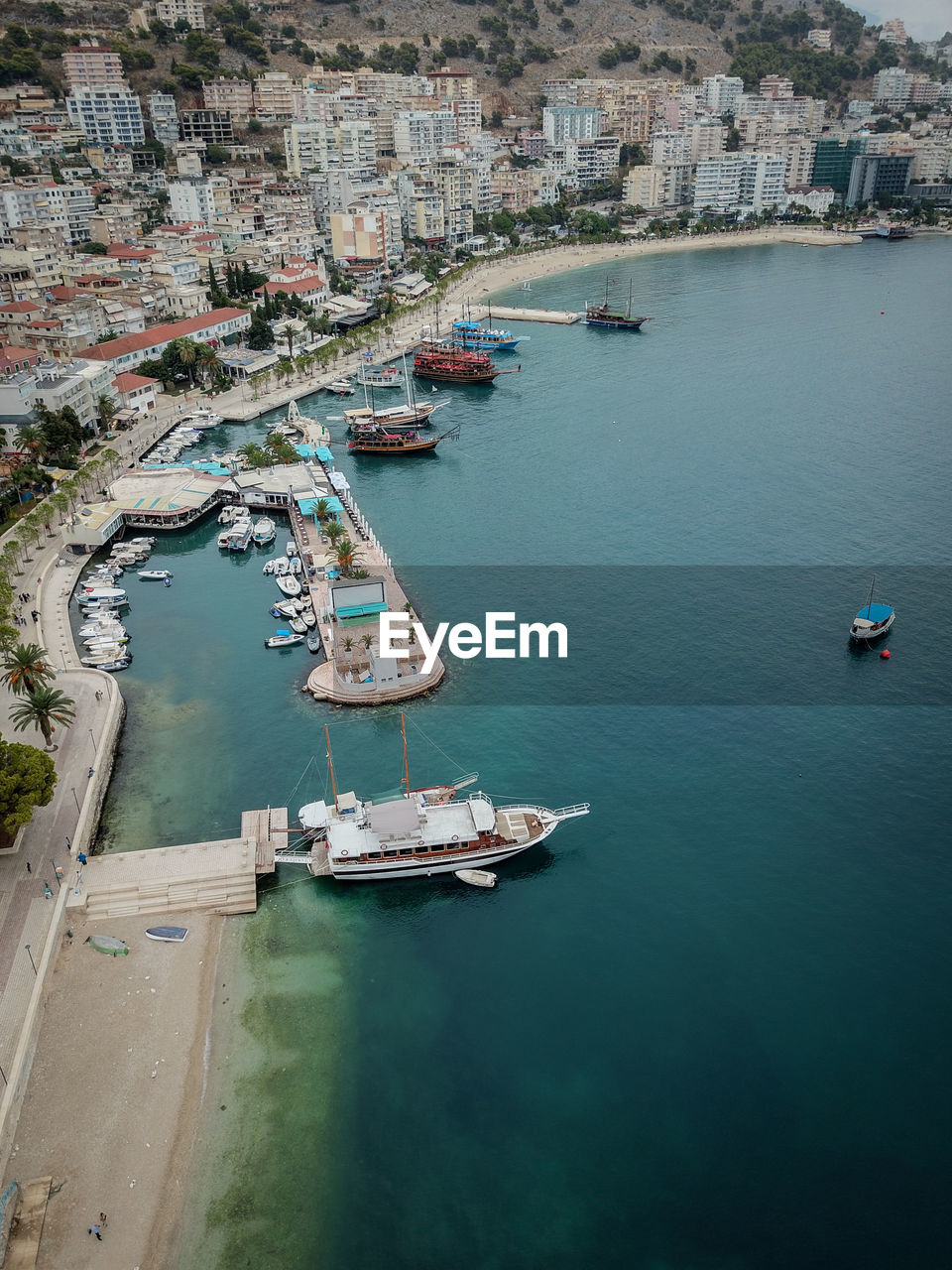 High angle view of sailboats moored on sea by buildings in city