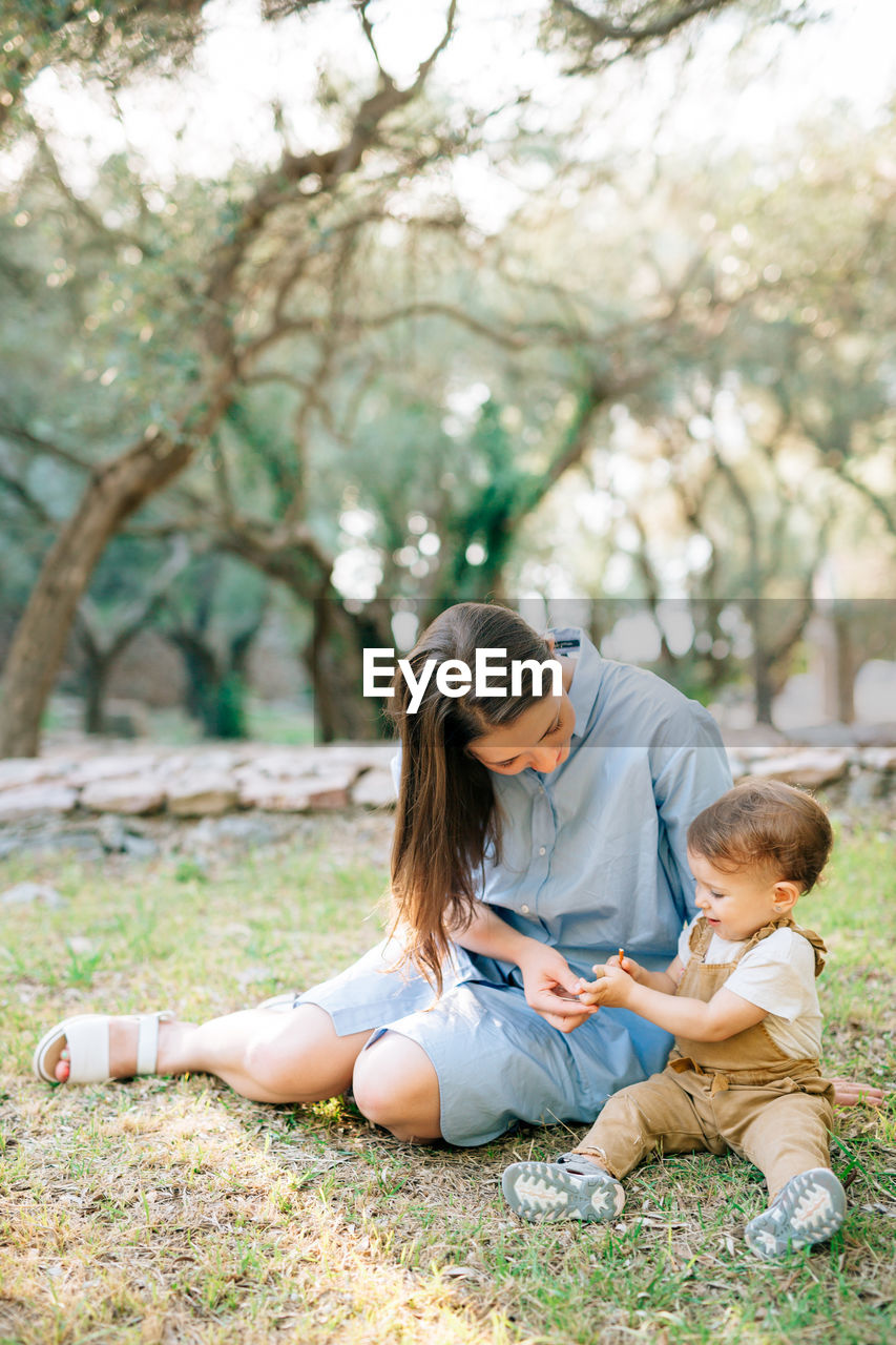 Mother and daughter sitting on grass in park