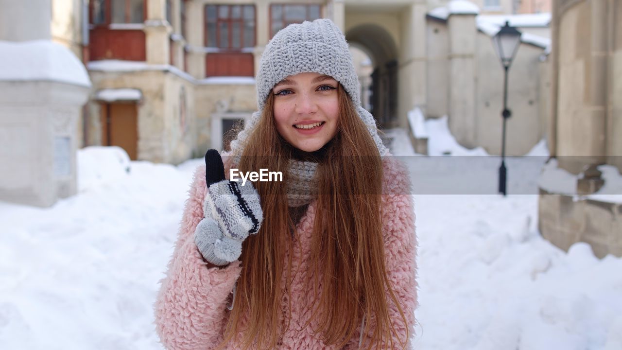 Portrait of young woman holding coffee cup while standing outdoors