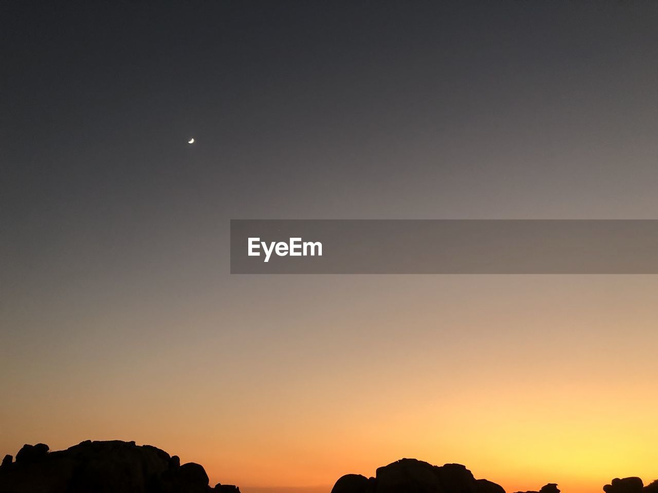 Low angle view of silhouette moon against sky at sunset