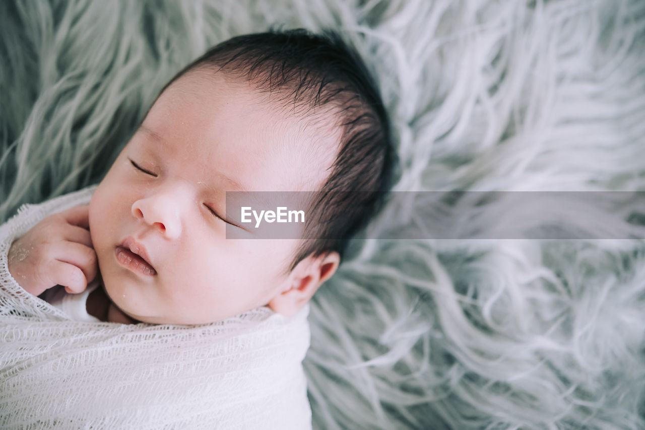 Close-up of baby sleeping in bed