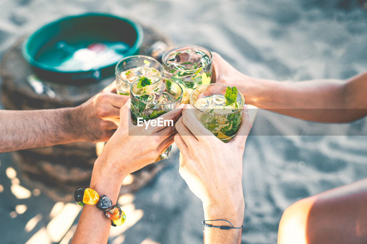 High angle view of group of people toasting holding glass with tropical  cocktails