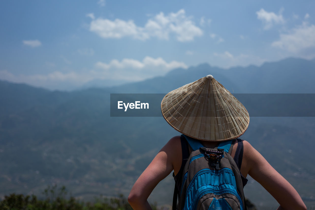 Rear view of backpacker wearing asian style conical hat looking at view