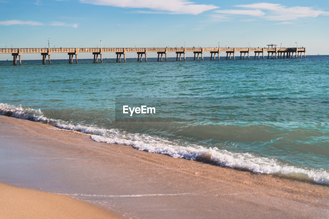 water, sea, beach, land, shore, wave, sky, pier, ocean, vacation, body of water, coast, horizon, nature, sand, architecture, scenics - nature, beauty in nature, cloud, breakwater, wind wave, built structure, bay, travel destinations, day, motion, travel, tranquility, coastline, outdoors, tranquil scene, shoal, no people, horizon over water, water sports, transportation, tourism, idyllic, sports, water's edge, holiday, trip, blue, walkway