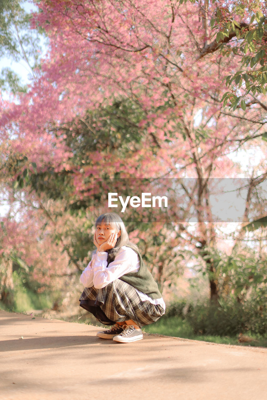 Portrait of woman standing by cherry tree in park