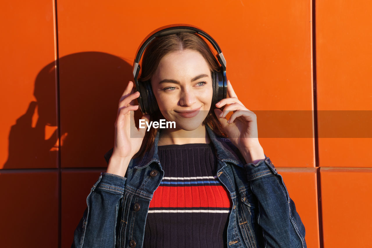 Pretty woman listening to music on headphones, outdoor hipster portrait against