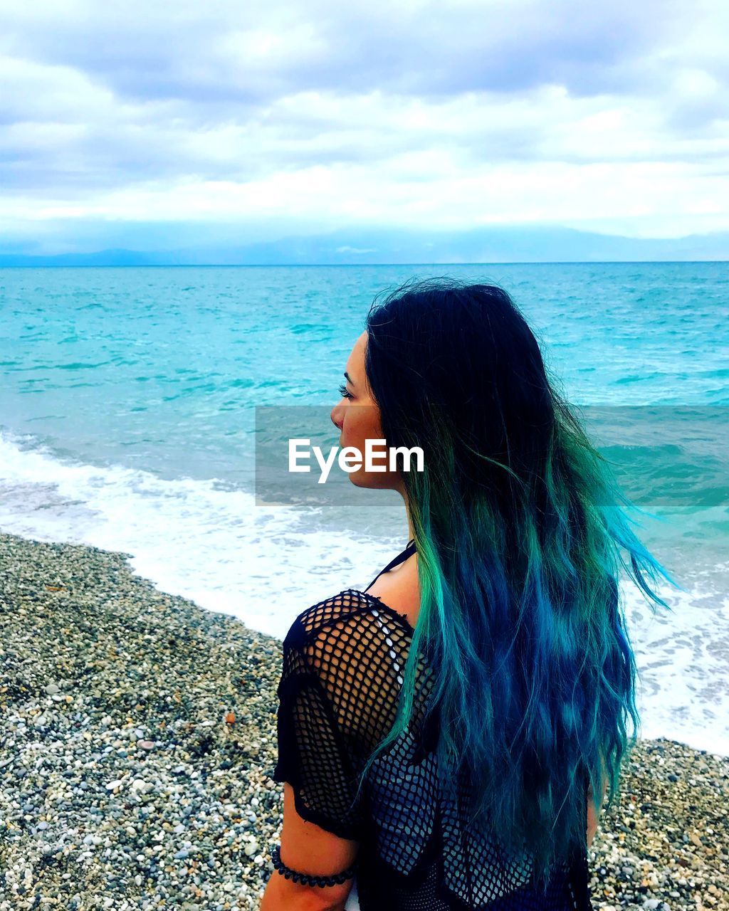 Rear view of woman with dyed hair at beach against sky