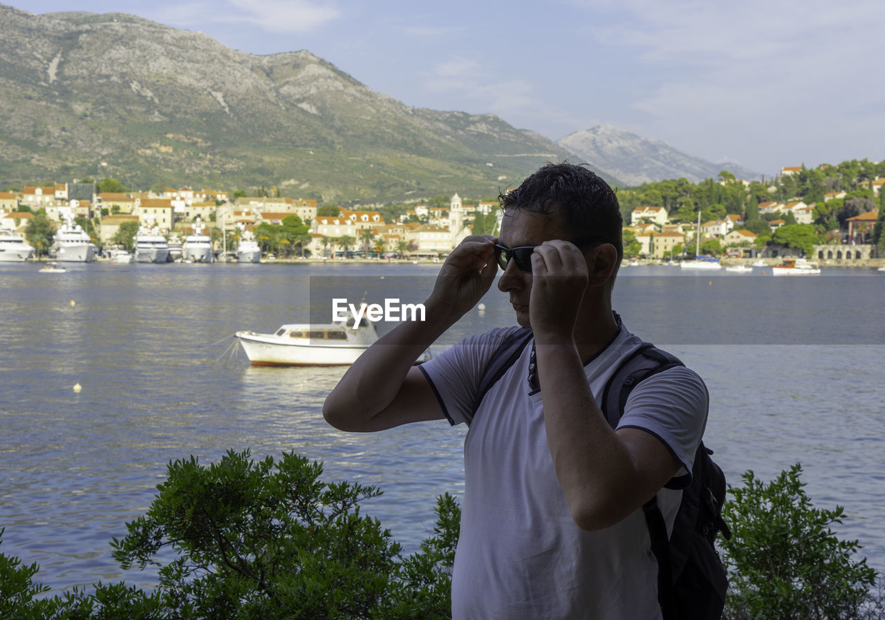 Mature man wearing sunglasses while standing against lake