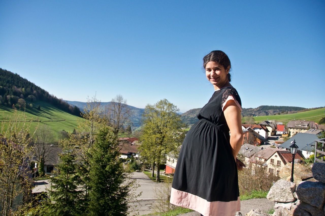 YOUNG WOMAN STANDING ON MOUNTAIN AGAINST CLEAR SKY