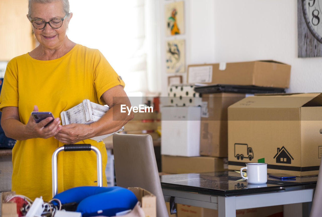 Smiling woman using phone standing at home