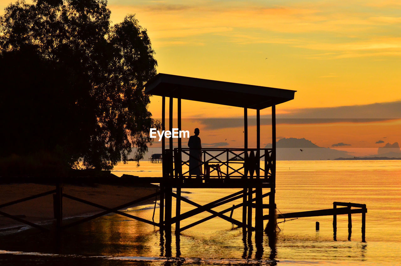 Amazing beautiful sunrise with silhouette wooden jetty at lubuk temiang beach,labuan ft,malaysia. 