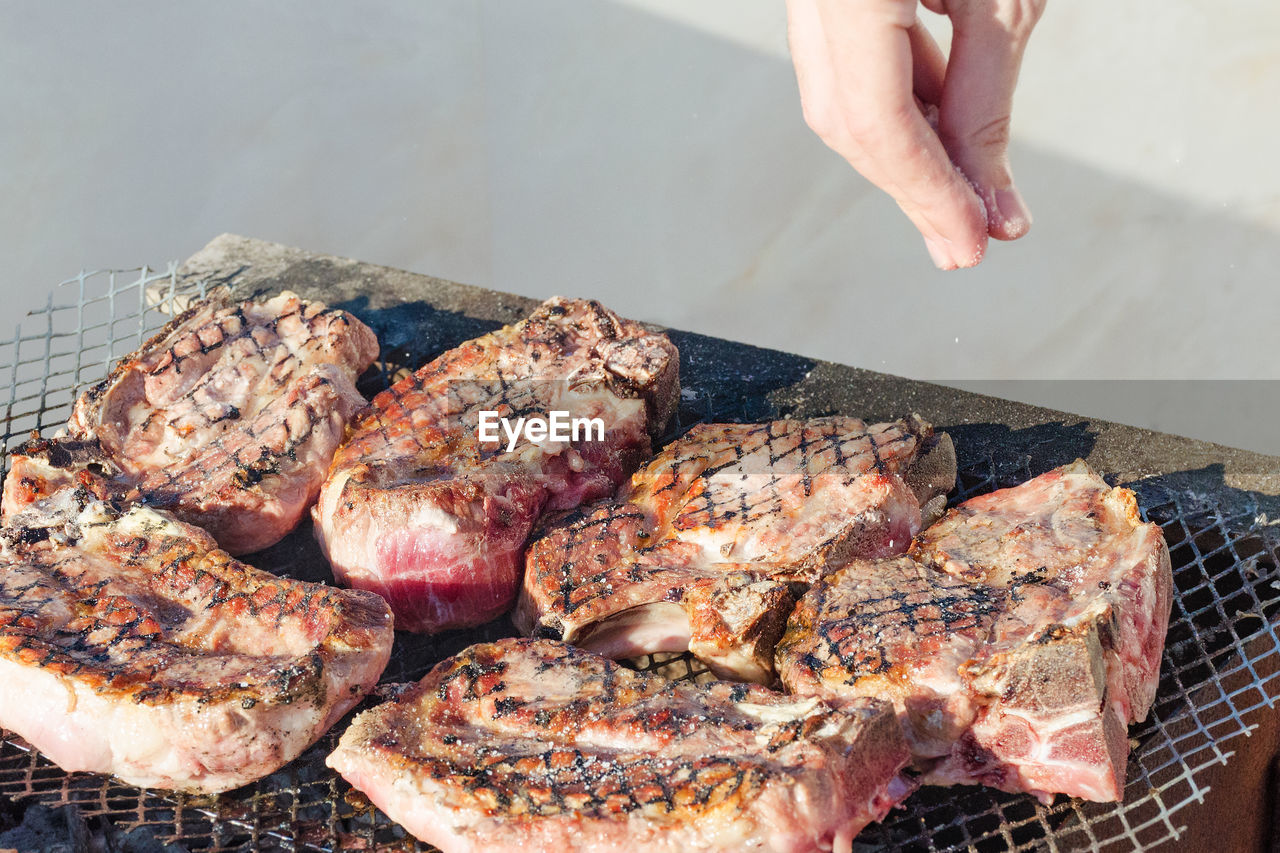 The meat is grilled. cooks hand salt steaks in a barbecue.