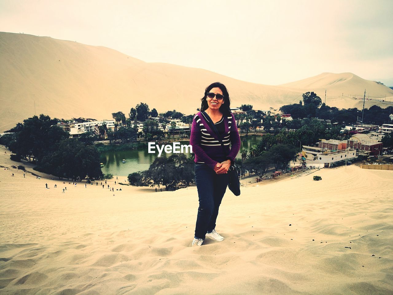 Portrait of woman in sunglasses standing on desert at oasis