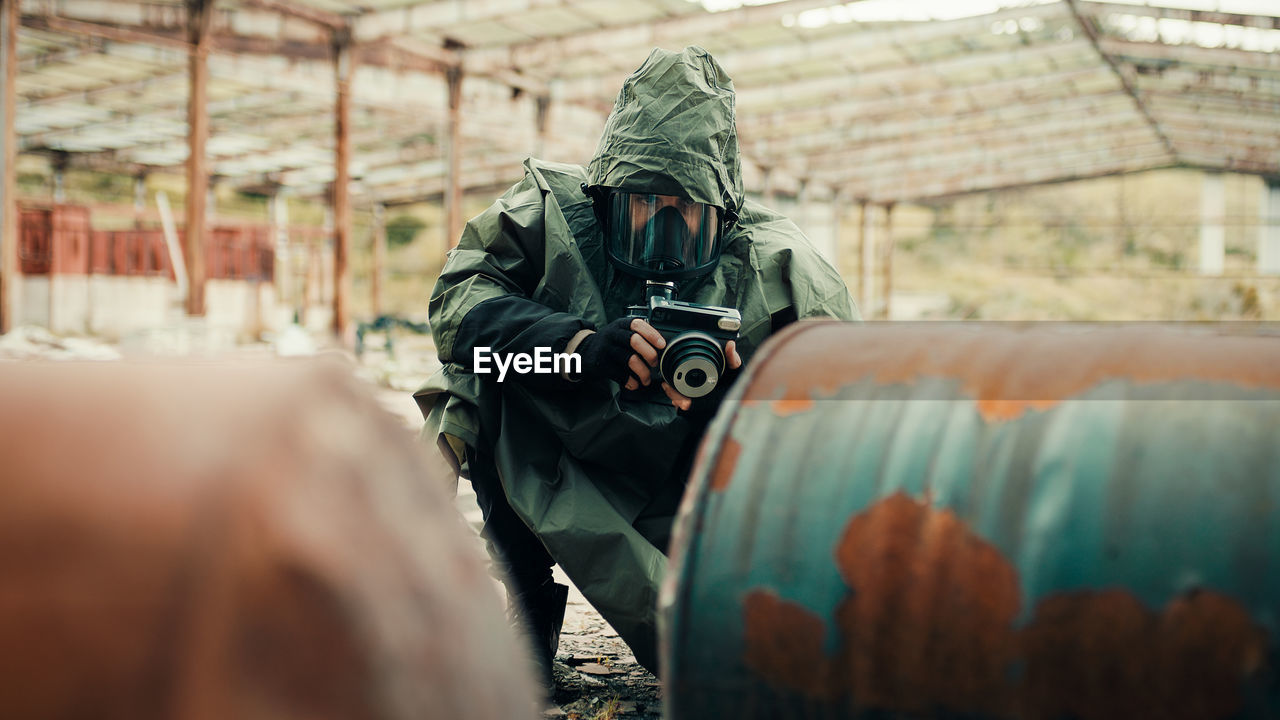 Man with gas mask photographs the radioactive barrels