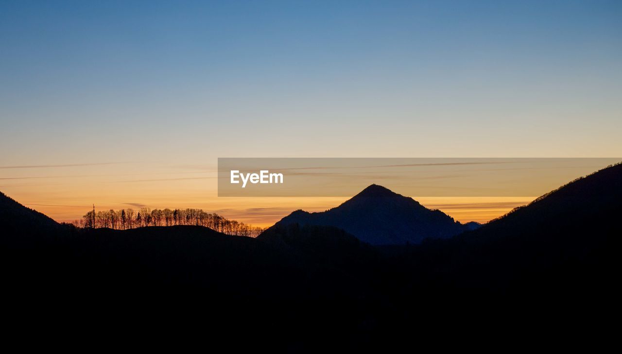 Scenic view of silhouette mountains against clear sky during sunset