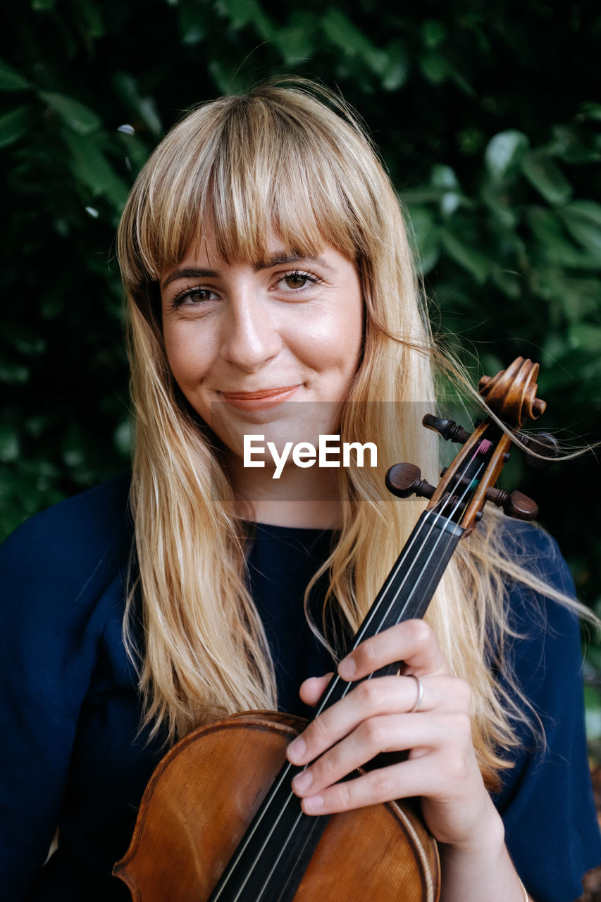 Portrait of smiling woman holding violin