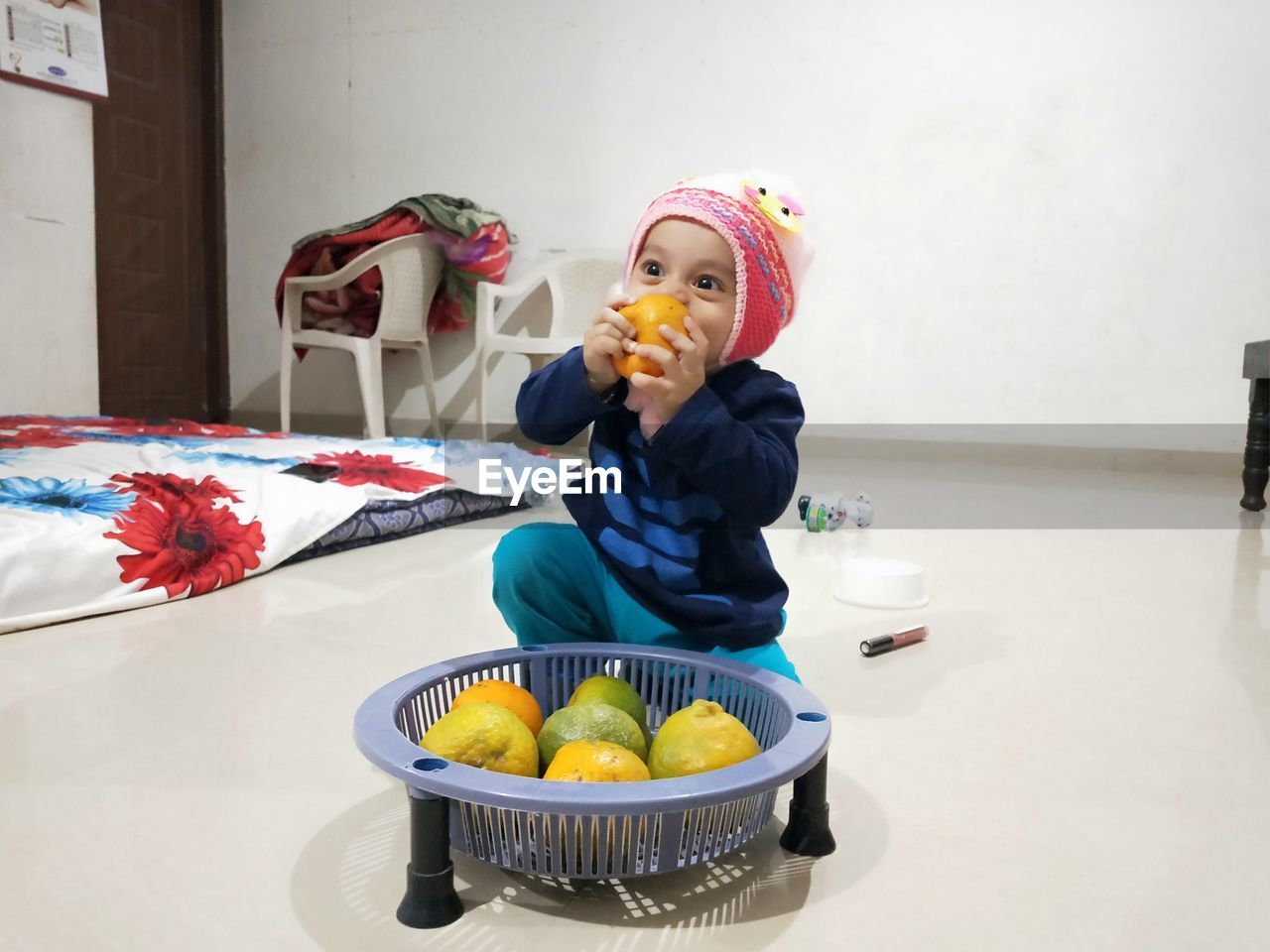 Cute boy eating orange fruit at home