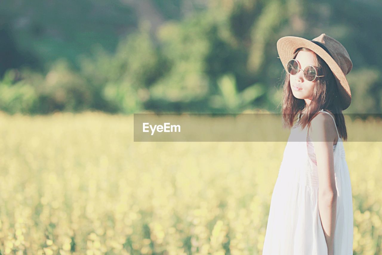 Girl wearing sunglasses and hat while standing on field