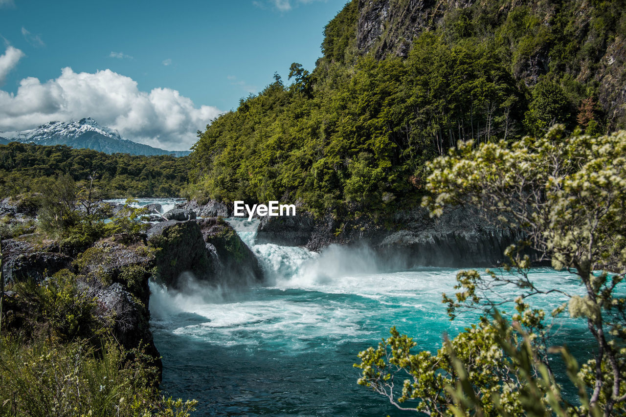 SCENIC VIEW OF WATERFALL IN FOREST AGAINST SKY