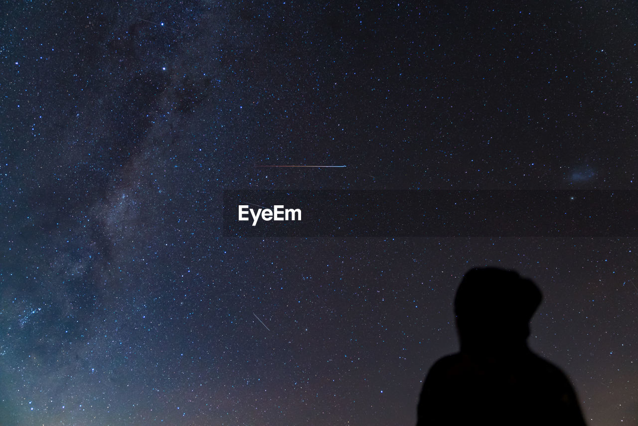 Low angle view of silhouette man against star field at night