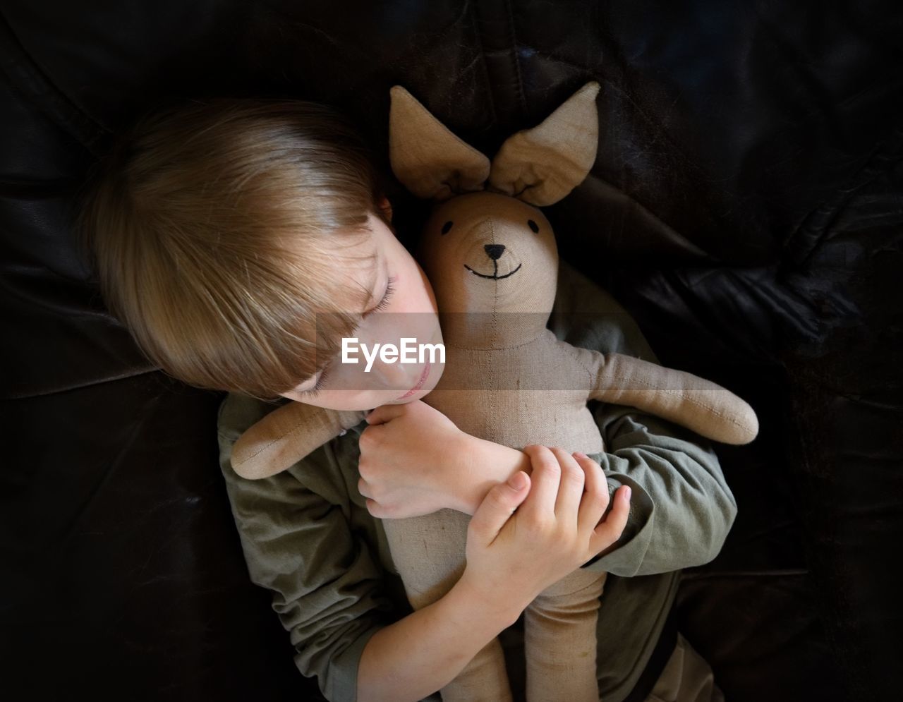 Directly above shot of boy embracing stuffed toy while lying on bed