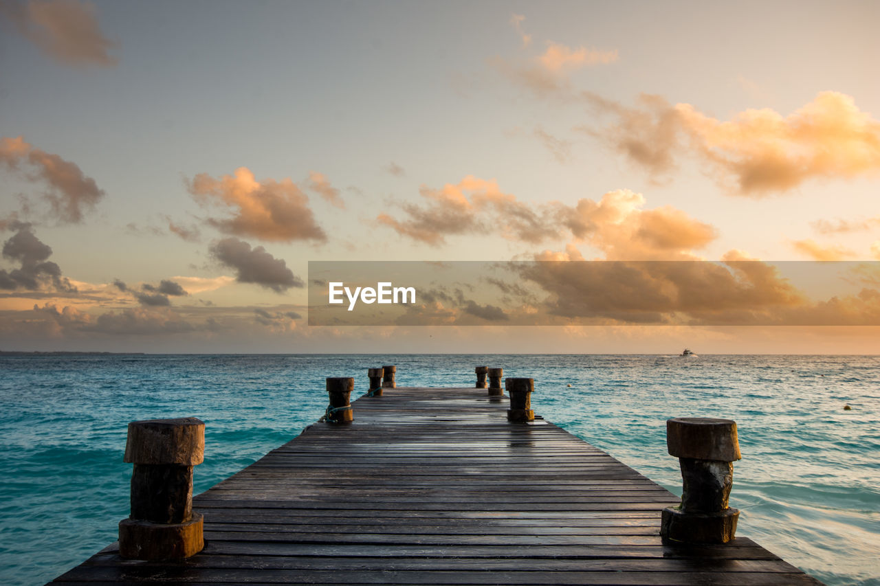 Pier over sea against sky during sunset