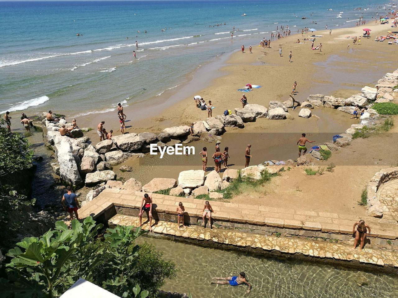 HIGH ANGLE VIEW OF PEOPLE ON BEACH AGAINST SEA