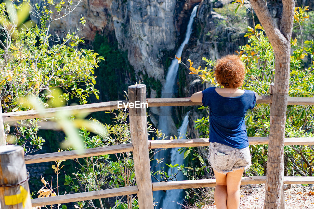 Rear view of woman standing against waterfall