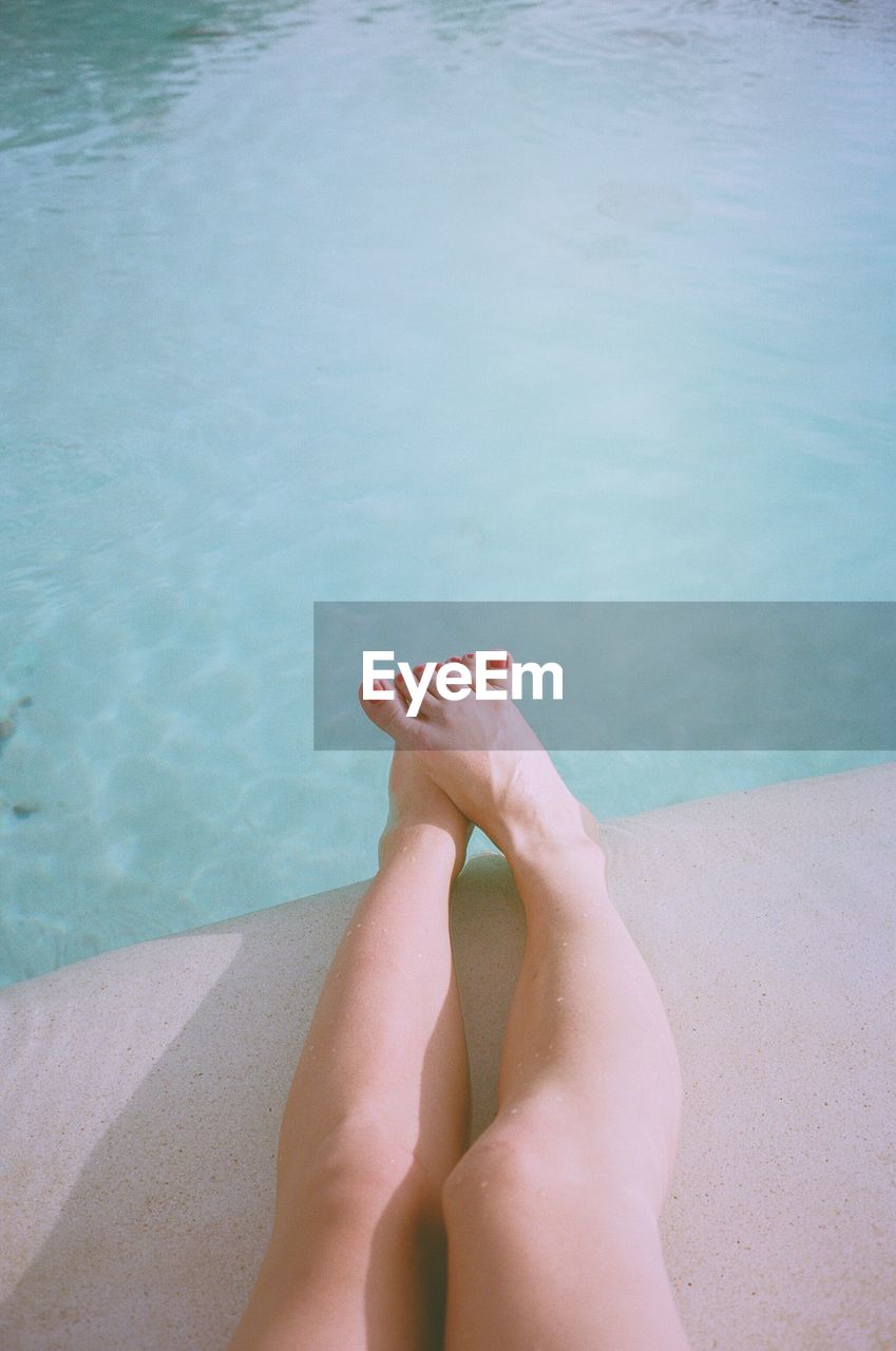 Low section of woman relaxing at poolside