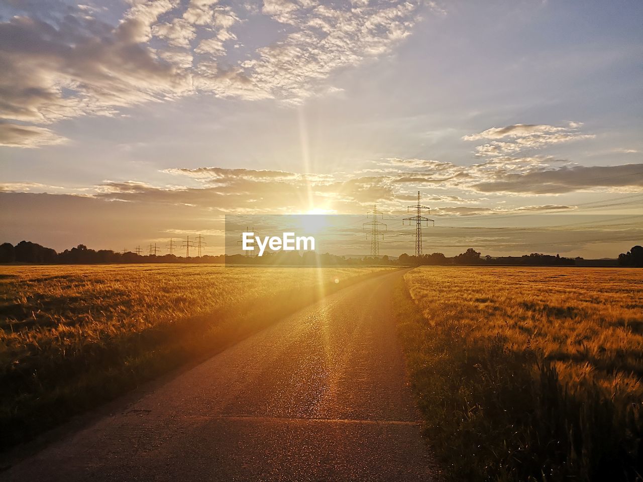 ROAD AMIDST FIELD AGAINST SKY AT SUNSET