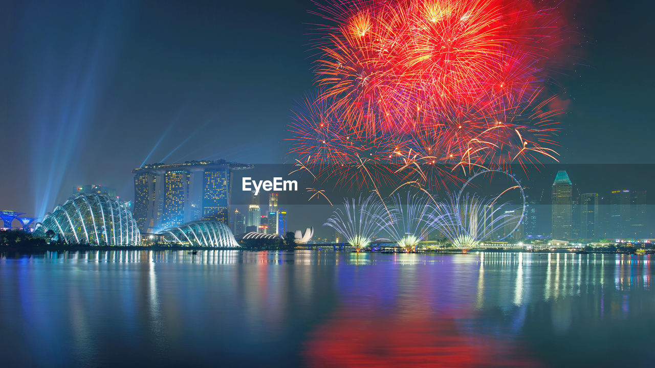 Firework display over river against sky at night