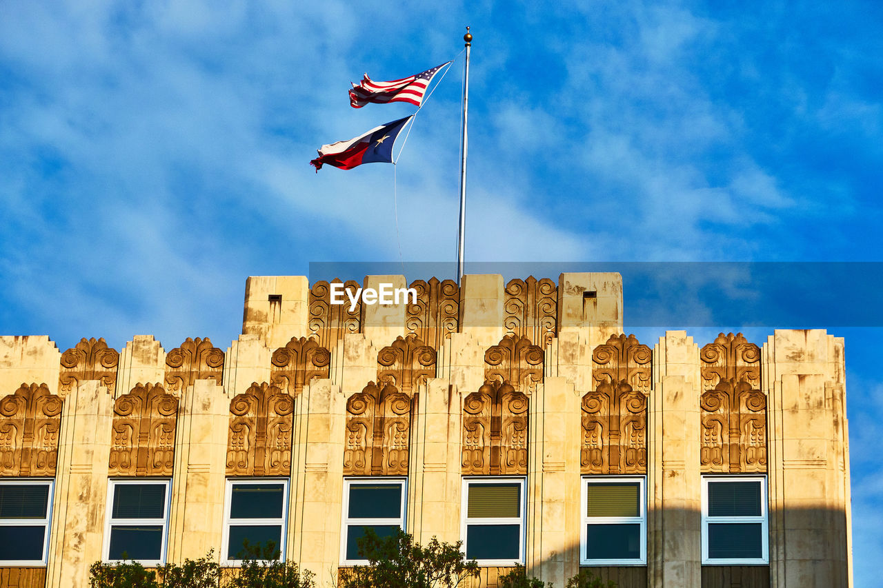 Low angle view of usa and texas flag against sky