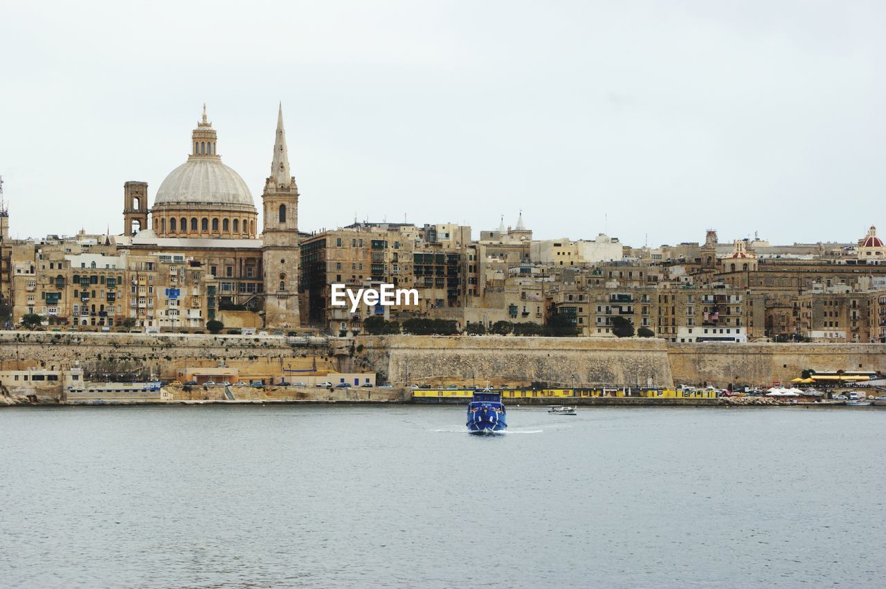 BOAT IN RIVER BY BUILDINGS IN CITY