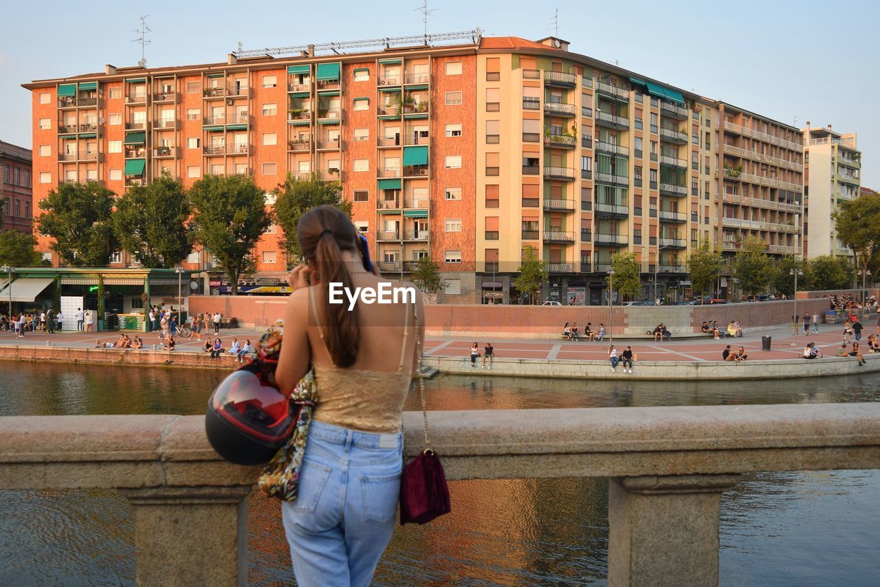 WOMAN STANDING BY BUILDING IN CITY