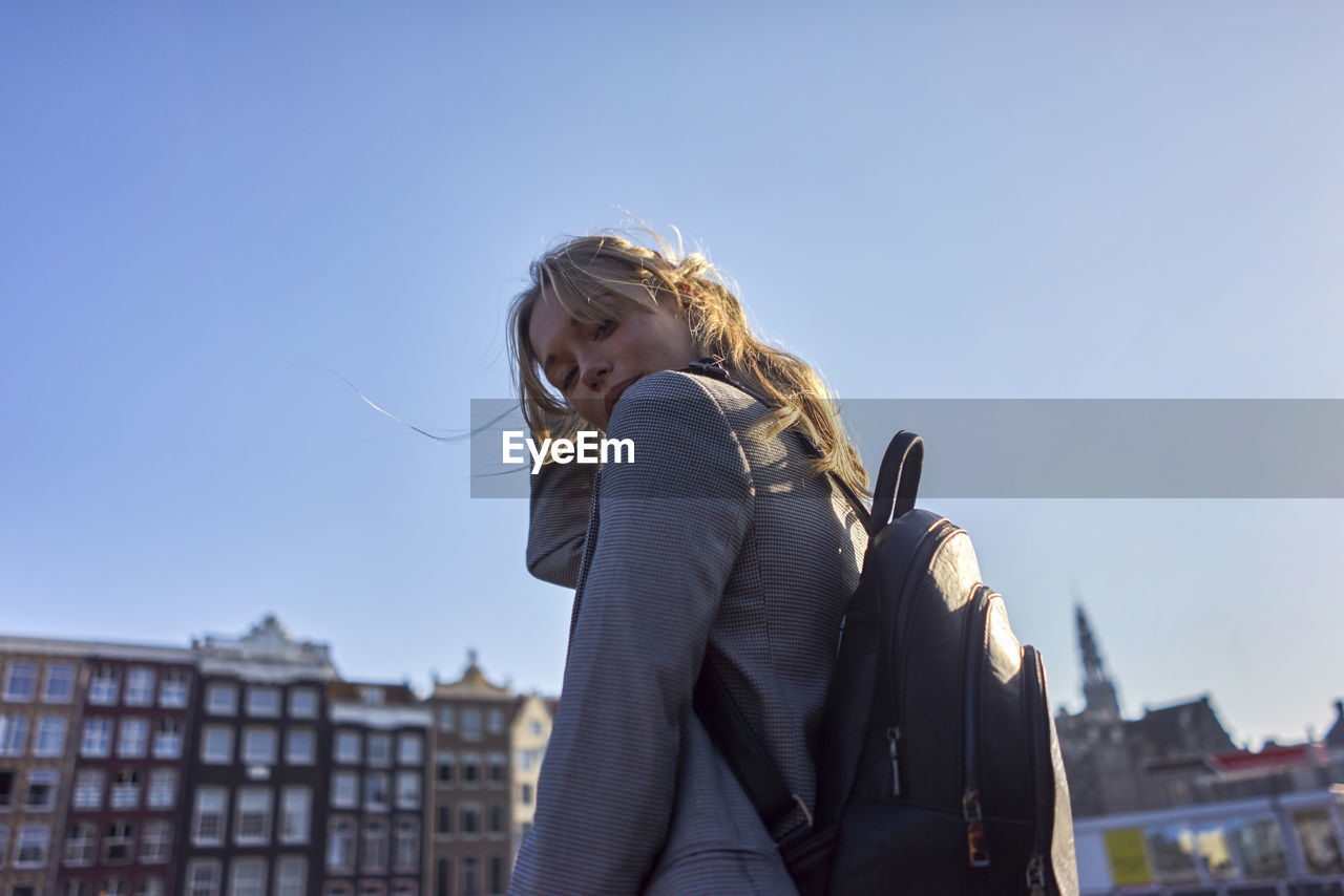 Portrait of woman standing against clear sky in city