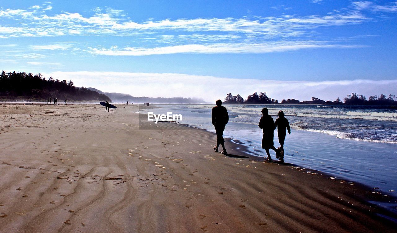 People walking on beach against sky